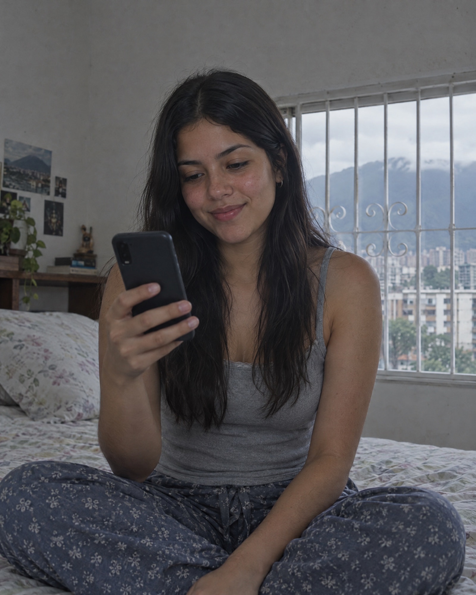 Una joven sentada en su cama en Caracas elige algo en su teléfono.